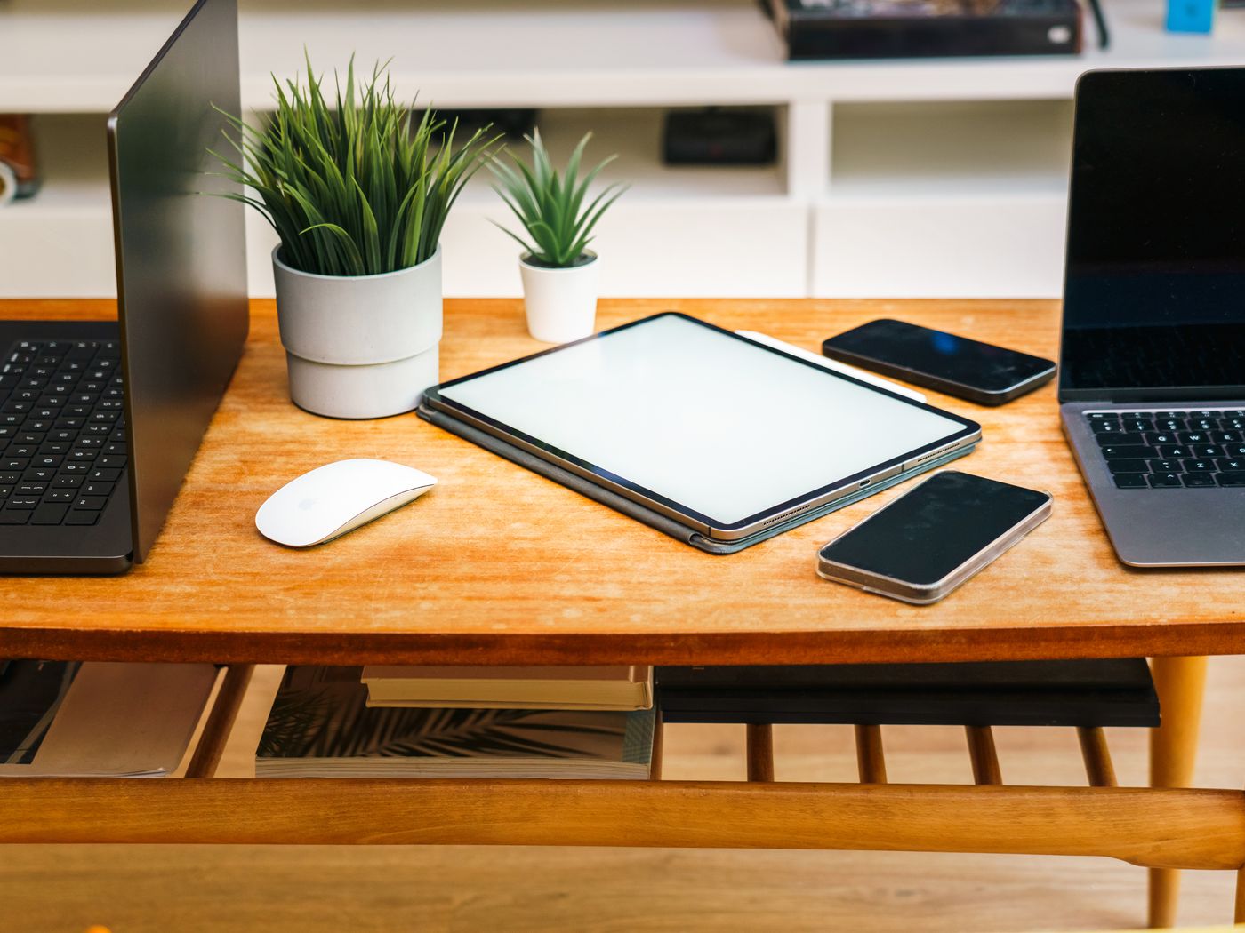 A laptop, a tablet and a phone side by side on a wooden desk, the same records on all three